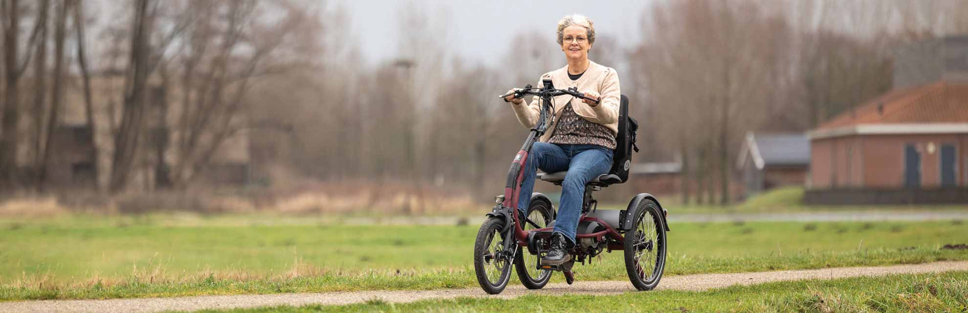 Lächelnde Frau sitzt auf einem E-Dreirad von Van Raam und schaut in die Kamera