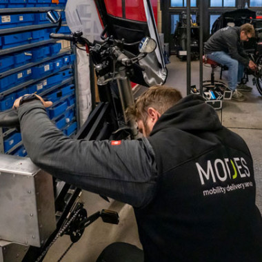 Serviceleiter Andre wartet ein gewerbliches Cargobike in der Fahrradwerkstatt mit MODES Weste