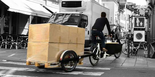 Cargobike fährt mit Fahrradanhänger für Europaletten durch die Fußgängerzone